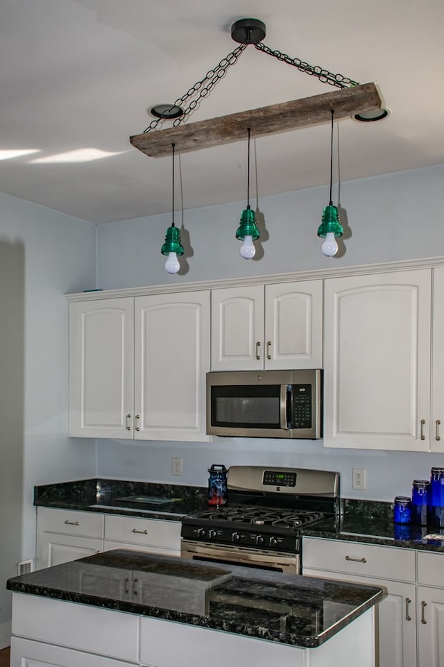 kitchen with stainless steel appliances, white cabinetry, and decorative light fixtures