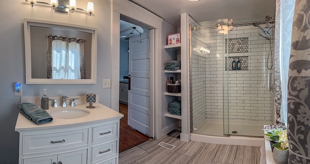 bathroom with a stall shower, wood finished floors, and vanity