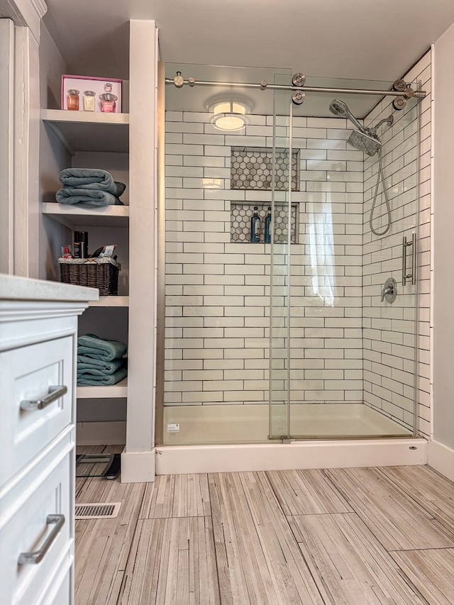 full bath featuring wood finish floors and a shower stall