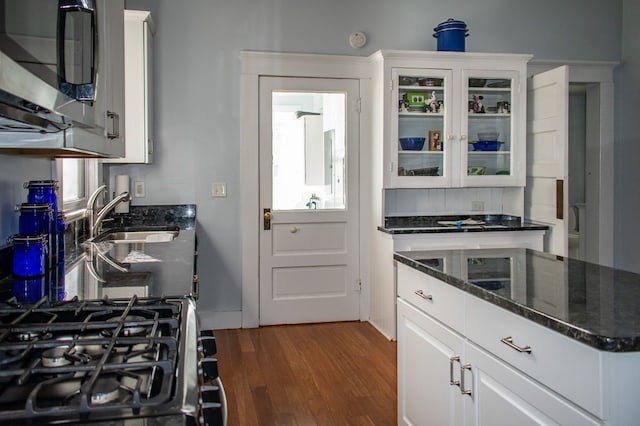 kitchen featuring glass insert cabinets, a sink, stainless steel microwave, dark wood finished floors, and gas range