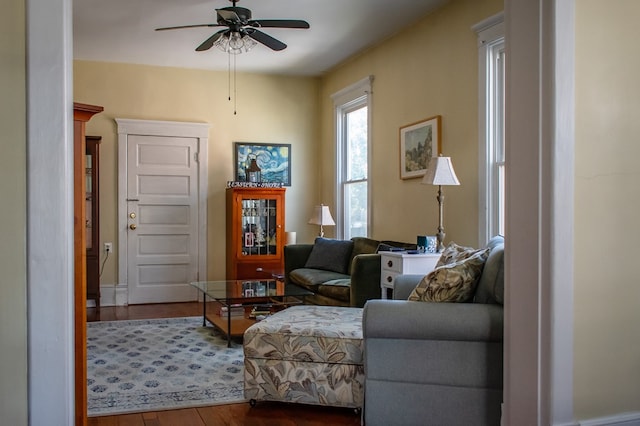 living area featuring ceiling fan and dark wood finished floors