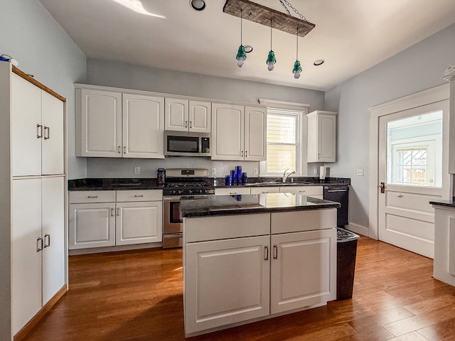 kitchen featuring appliances with stainless steel finishes, white cabinetry, a sink, and wood finished floors