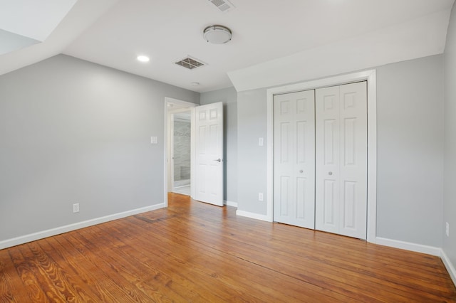 unfurnished bedroom with lofted ceiling, wood-type flooring, and a closet