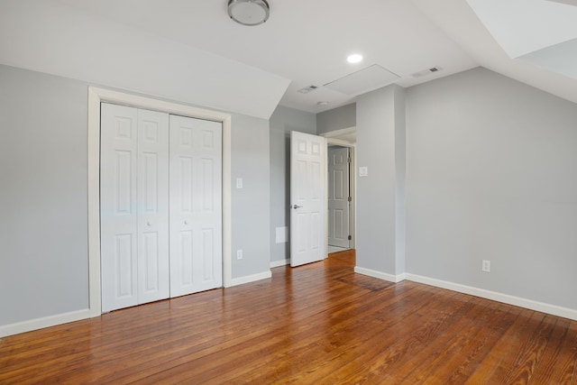 unfurnished bedroom featuring wood-type flooring, a closet, and lofted ceiling