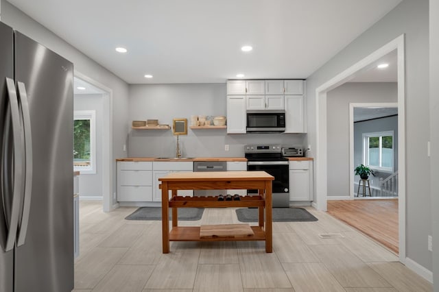 kitchen featuring white cabinets, appliances with stainless steel finishes, a healthy amount of sunlight, and sink