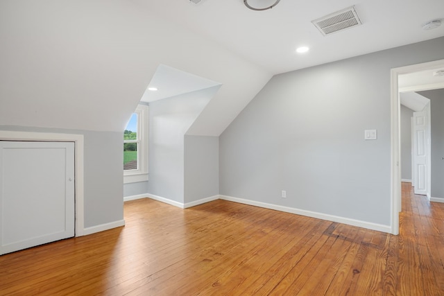 additional living space with light hardwood / wood-style floors and lofted ceiling