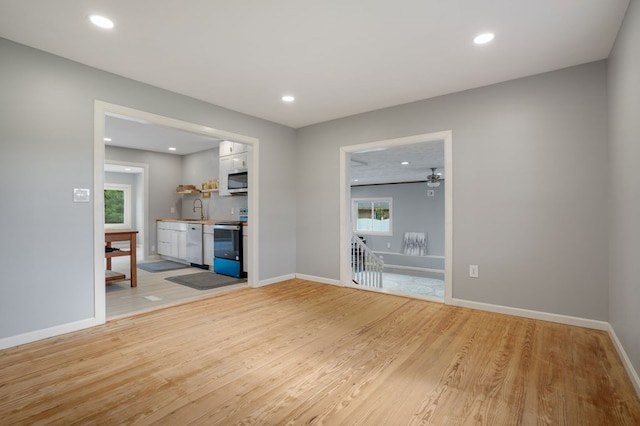 unfurnished living room with plenty of natural light, sink, and light hardwood / wood-style flooring