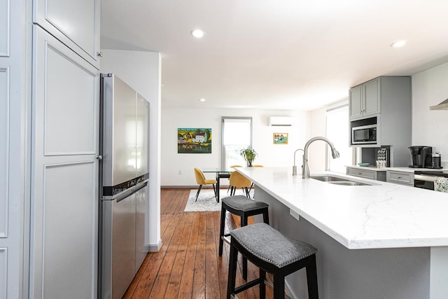 kitchen with a kitchen bar, sink, appliances with stainless steel finishes, gray cabinets, and a wealth of natural light