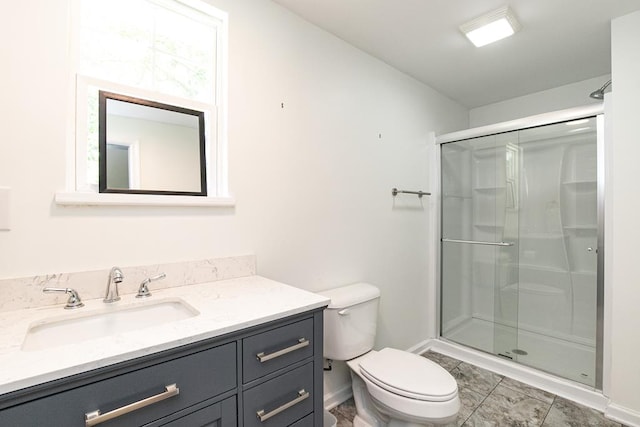 bathroom featuring toilet, vanity, and a shower with shower door