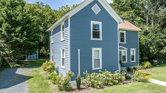 view of side of home featuring a storage shed and a lawn