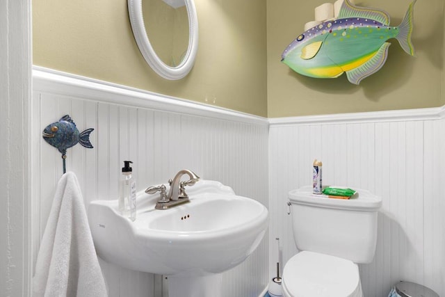 bathroom with a sink, a wainscoted wall, and toilet