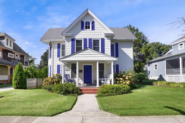 view of front facade featuring roof with shingles, covered porch, and a front lawn