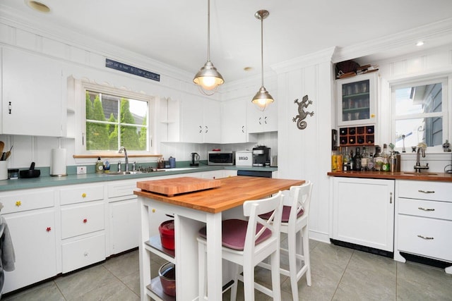 kitchen featuring butcher block countertops, a sink, open shelves, white cabinets, and crown molding