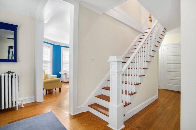 stairway with crown molding, hardwood / wood-style flooring, radiator, and baseboards