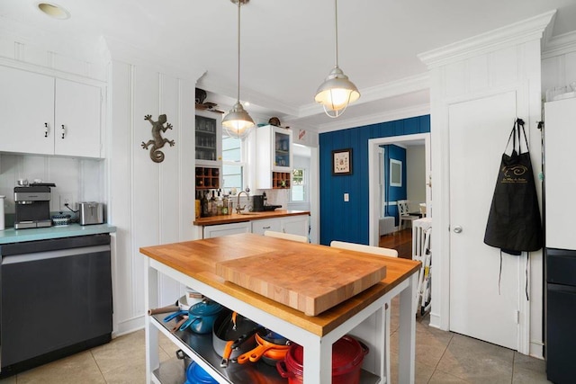 kitchen with decorative light fixtures, light tile patterned flooring, white cabinets, butcher block counters, and crown molding