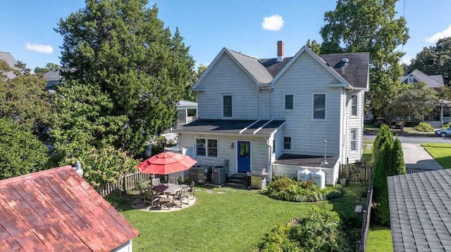 rear view of house with fence, a chimney, entry steps, central air condition unit, and a lawn