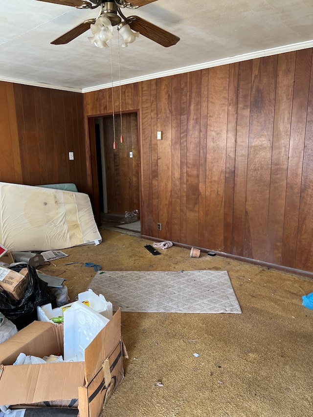 unfurnished living room featuring ceiling fan, wood walls, and ornamental molding