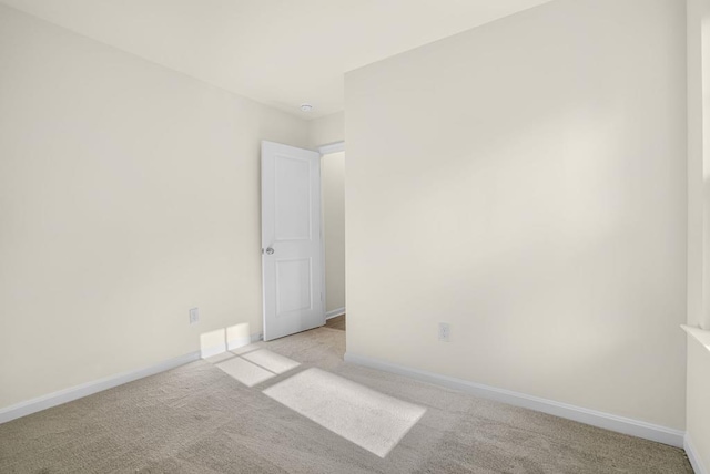 spare room featuring carpet and baseboards