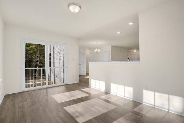 unfurnished room featuring baseboards, a chandelier, wood finished floors, and recessed lighting