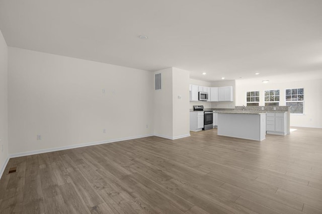 unfurnished living room with light wood-style floors, baseboards, and visible vents