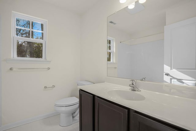 bathroom featuring visible vents, toilet, vanity, baseboards, and walk in shower