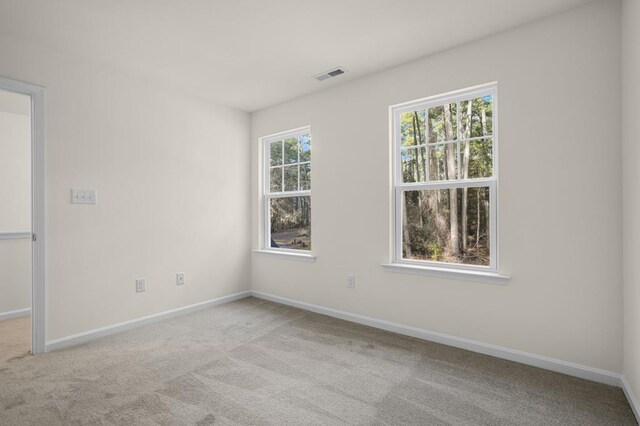 carpeted spare room with baseboards and visible vents