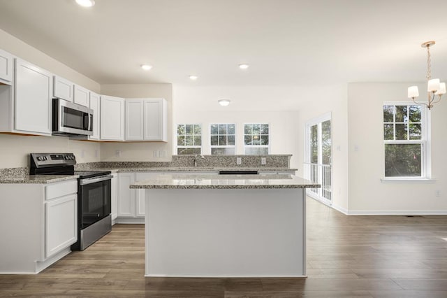 kitchen with light stone counters, recessed lighting, appliances with stainless steel finishes, a sink, and wood finished floors