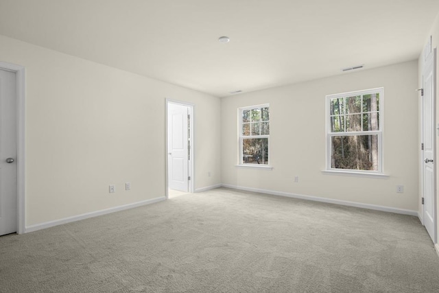 spare room with baseboards, visible vents, and light colored carpet