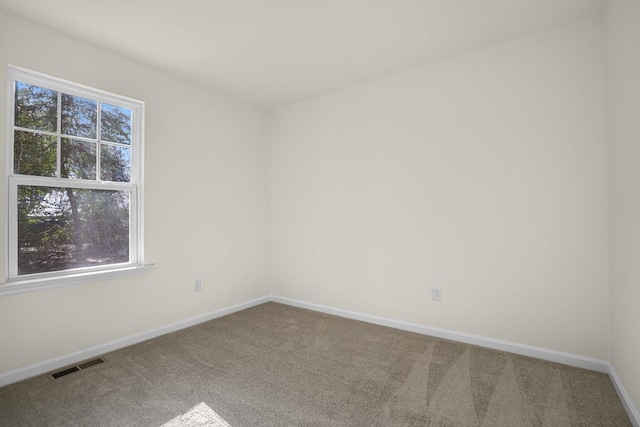 spare room featuring carpet flooring, visible vents, and baseboards