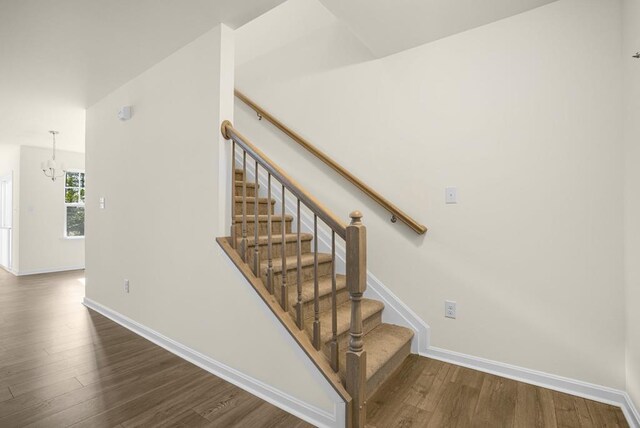 stairway with baseboards, a chandelier, and wood finished floors