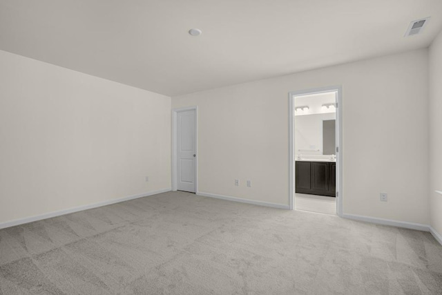 spare room featuring baseboards, visible vents, and light colored carpet