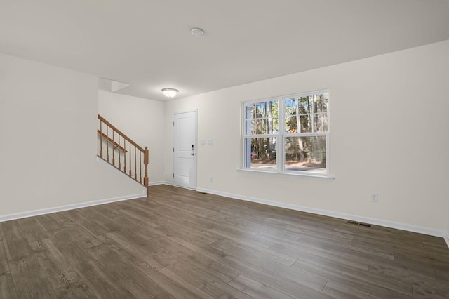 foyer entrance featuring stairs, dark wood-type flooring, visible vents, and baseboards