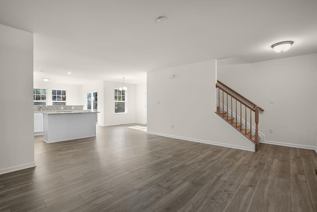 unfurnished living room with dark wood finished floors, baseboards, and stairs