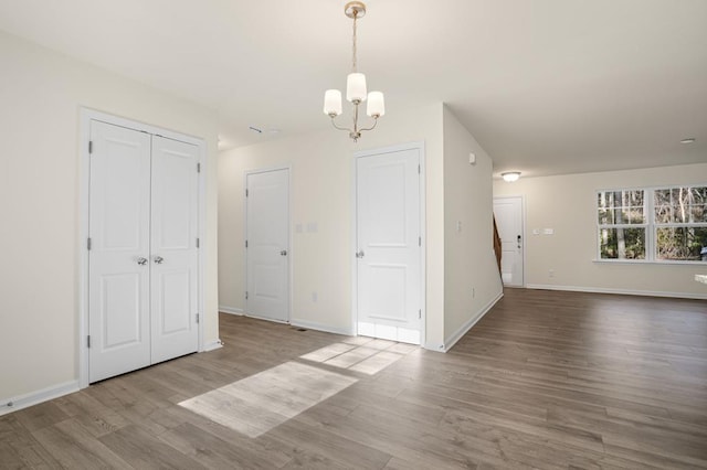 spare room featuring a chandelier, wood finished floors, and baseboards