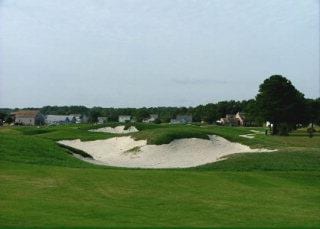 view of community featuring view of golf course and a yard