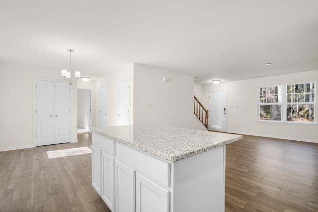 kitchen featuring baseboards, wood finished floors, white cabinets, and a center island