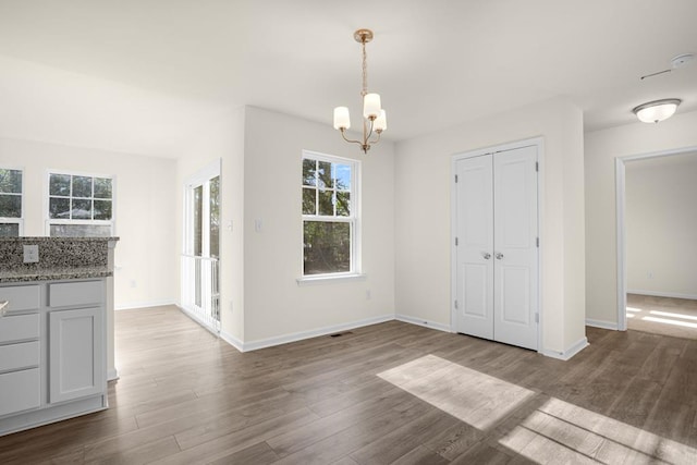 unfurnished dining area with visible vents, baseboards, and wood finished floors