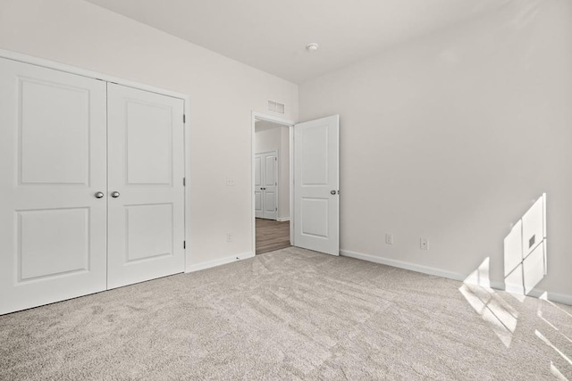 unfurnished bedroom featuring light carpet and a closet