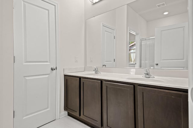 bathroom with tile patterned flooring, vanity, and a shower with door