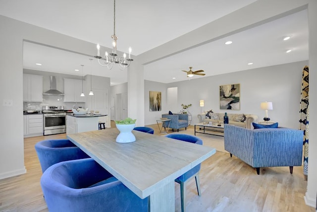 dining room with ceiling fan with notable chandelier and light hardwood / wood-style floors