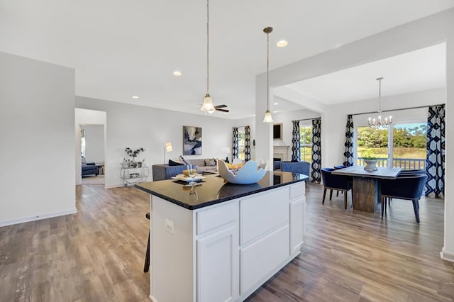 kitchen featuring white cabinets, ceiling fan with notable chandelier, a kitchen island, and light wood-type flooring