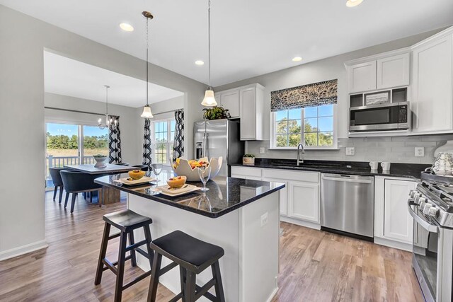 kitchen with pendant lighting, white cabinets, stainless steel appliances, and a kitchen island