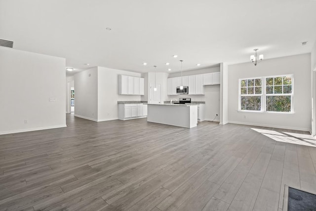 unfurnished living room with hardwood / wood-style floors and a chandelier