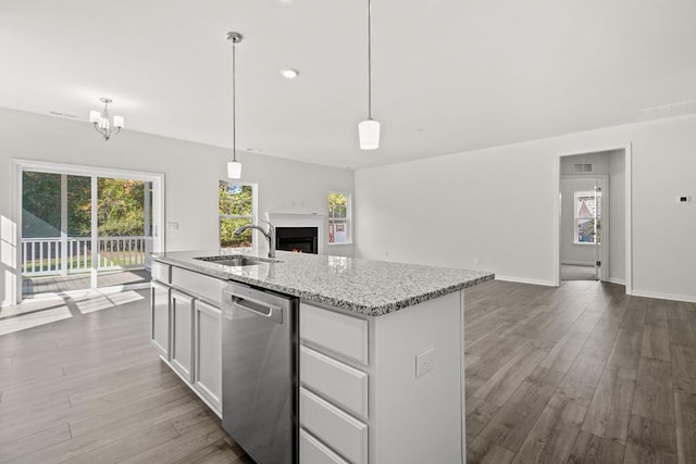 kitchen featuring pendant lighting, dishwasher, white cabinets, sink, and light stone countertops