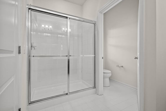 bathroom featuring tile patterned flooring, toilet, and a shower with door