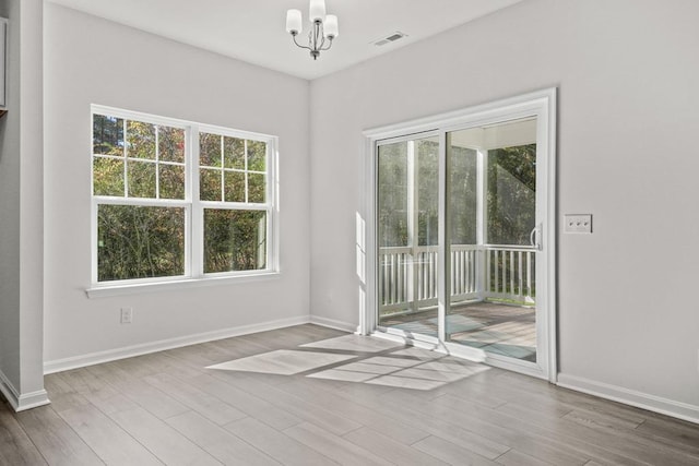 unfurnished room with hardwood / wood-style floors and an inviting chandelier