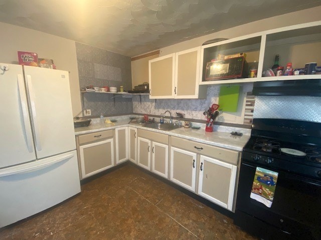 kitchen featuring exhaust hood, sink, white fridge, white cabinetry, and gas stove