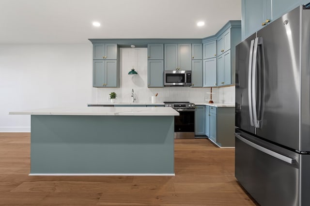 kitchen with light stone counters, sink, light wood-type flooring, and appliances with stainless steel finishes