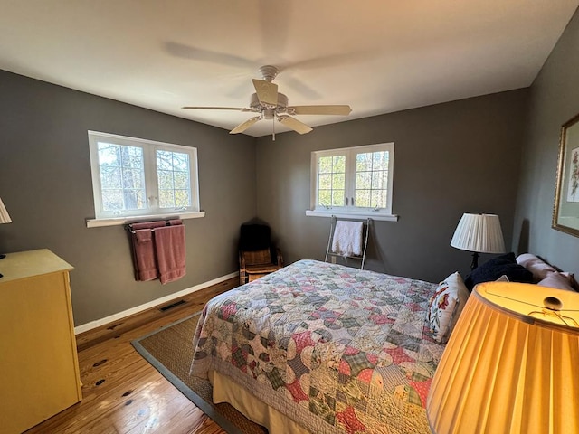 bedroom with light wood-style floors, baseboards, visible vents, and a ceiling fan