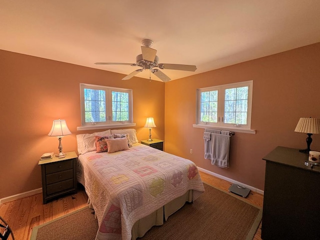 bedroom with a ceiling fan, baseboards, and wood finished floors